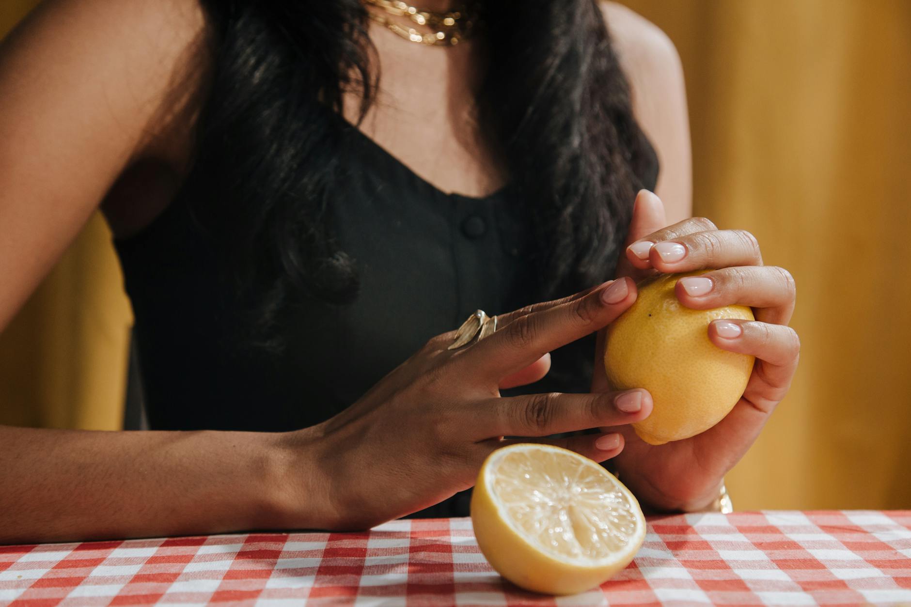 A hand holding a fresh lemon against a vivid yellow background, symbolizing renewal and fresh starts after medical recovery.