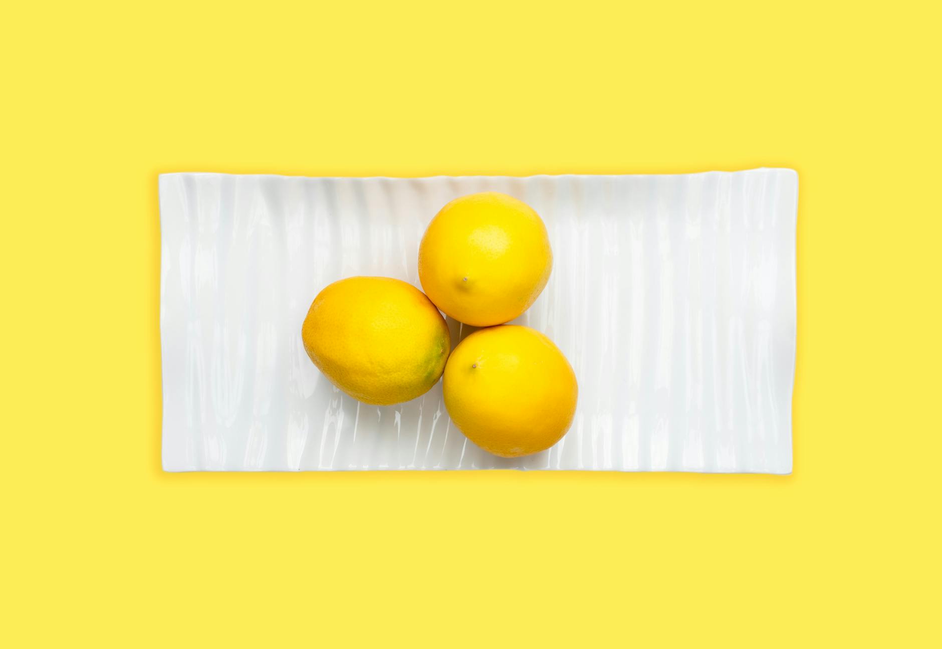 Fresh lemons arranged on a white plate, symbolizing the gentle, natural sensation of clitoral suction toys.