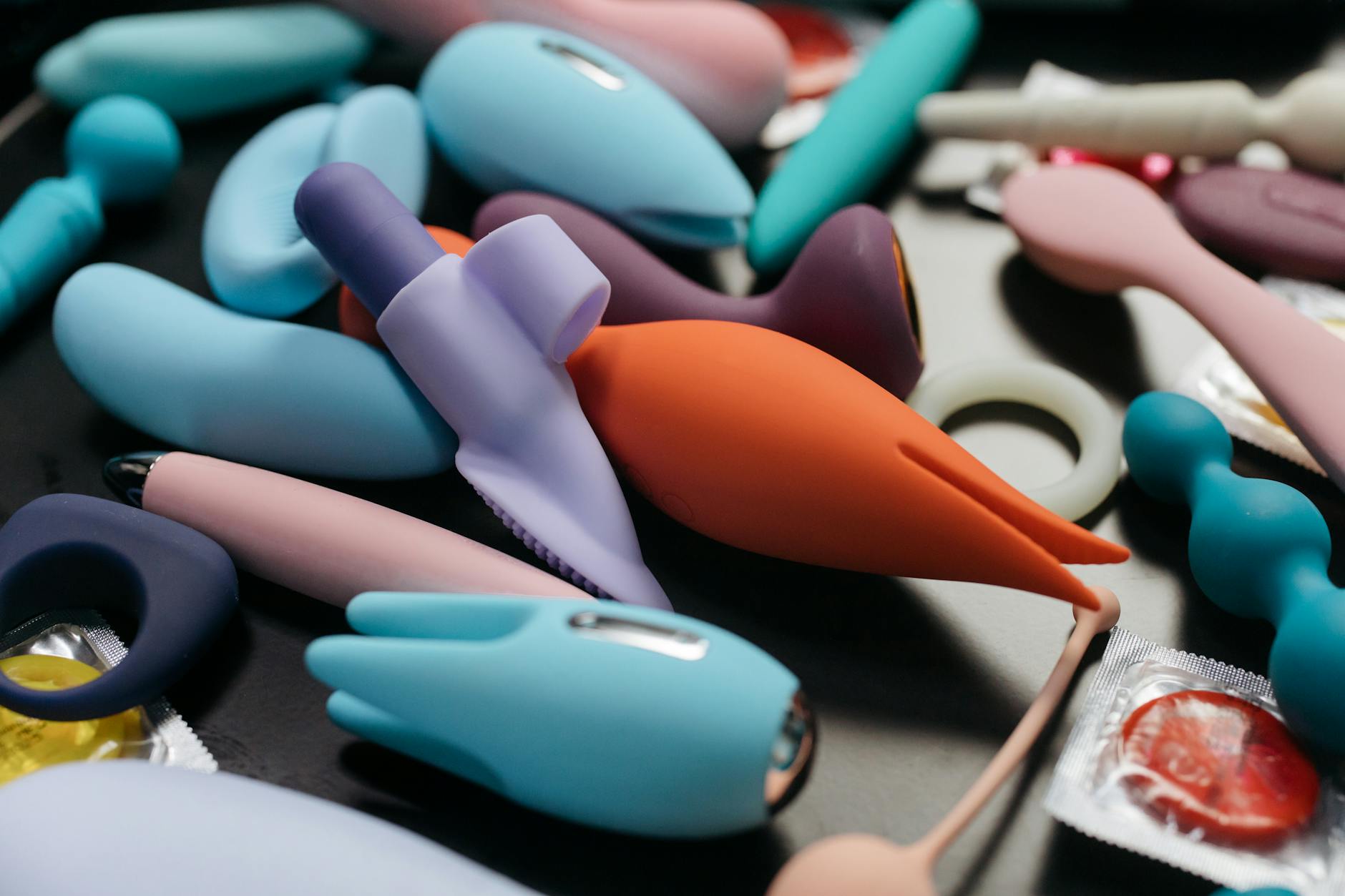 Close-up of a blue silicone vibrator held in hand against a purple background