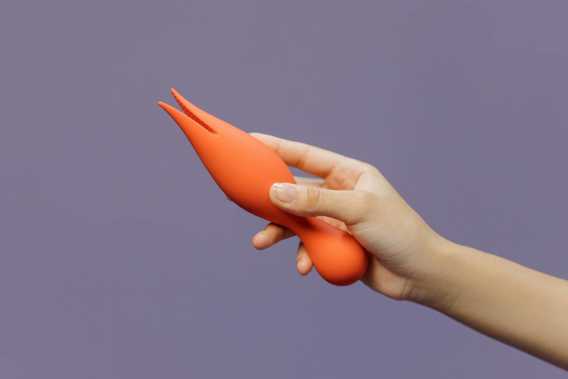 A hand holding a vibrator against a minimalistic backdrop, showcasing modern sensuality and self-care.