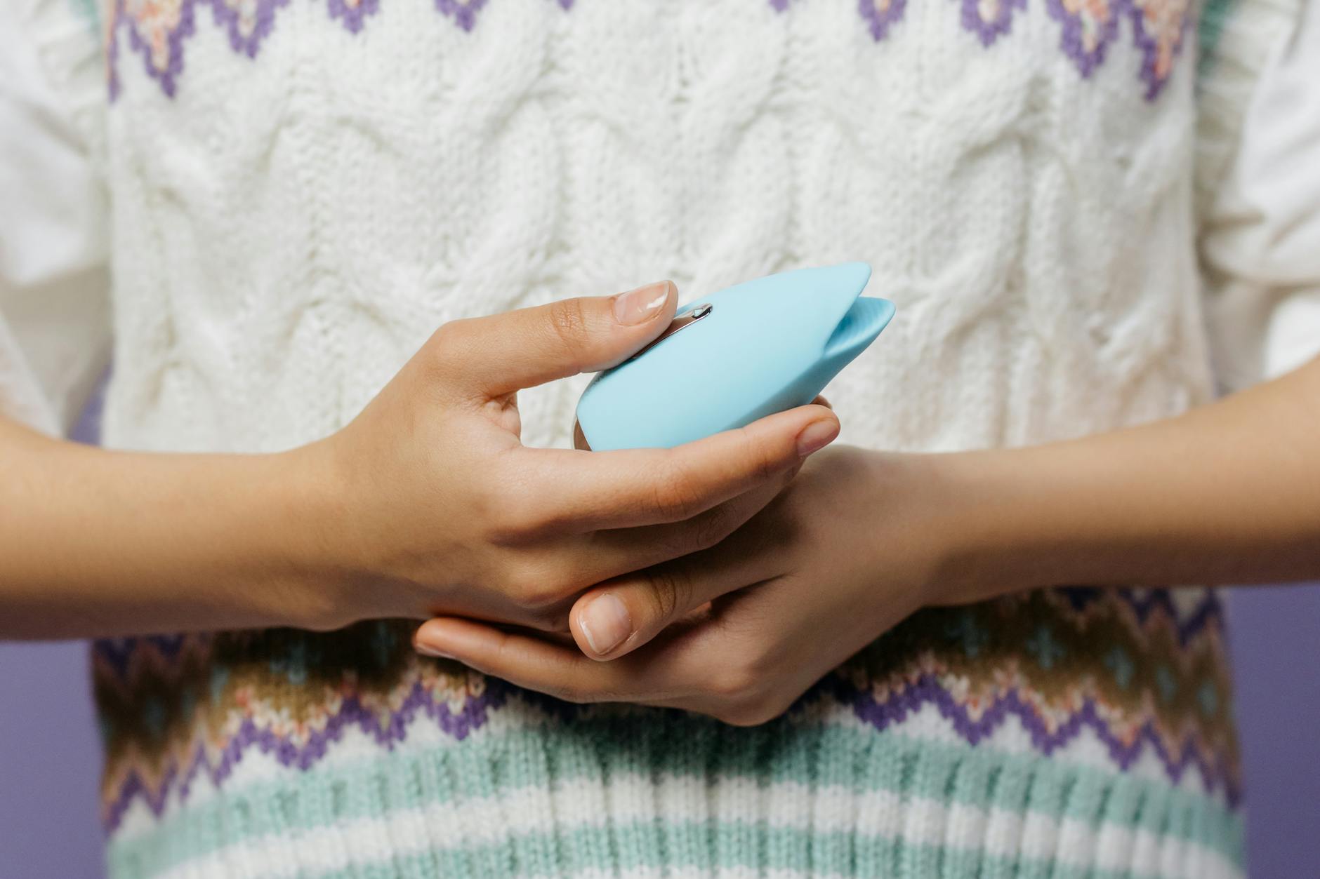 Close-up of hands holding a sleek blue vibrator, representing intimate reconnection with a partner.