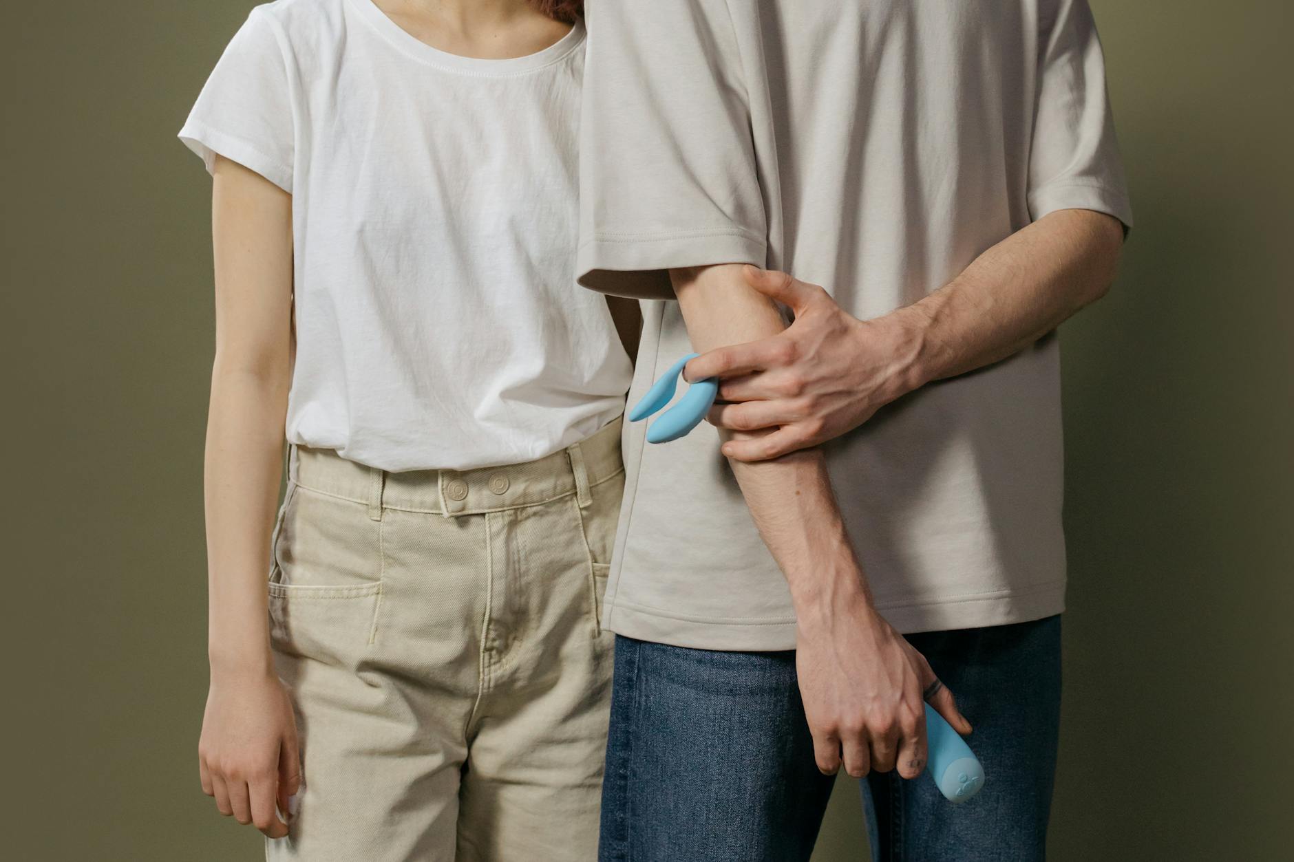 Woman holding blue and pink clitoral vibrators, considering which style suits her body