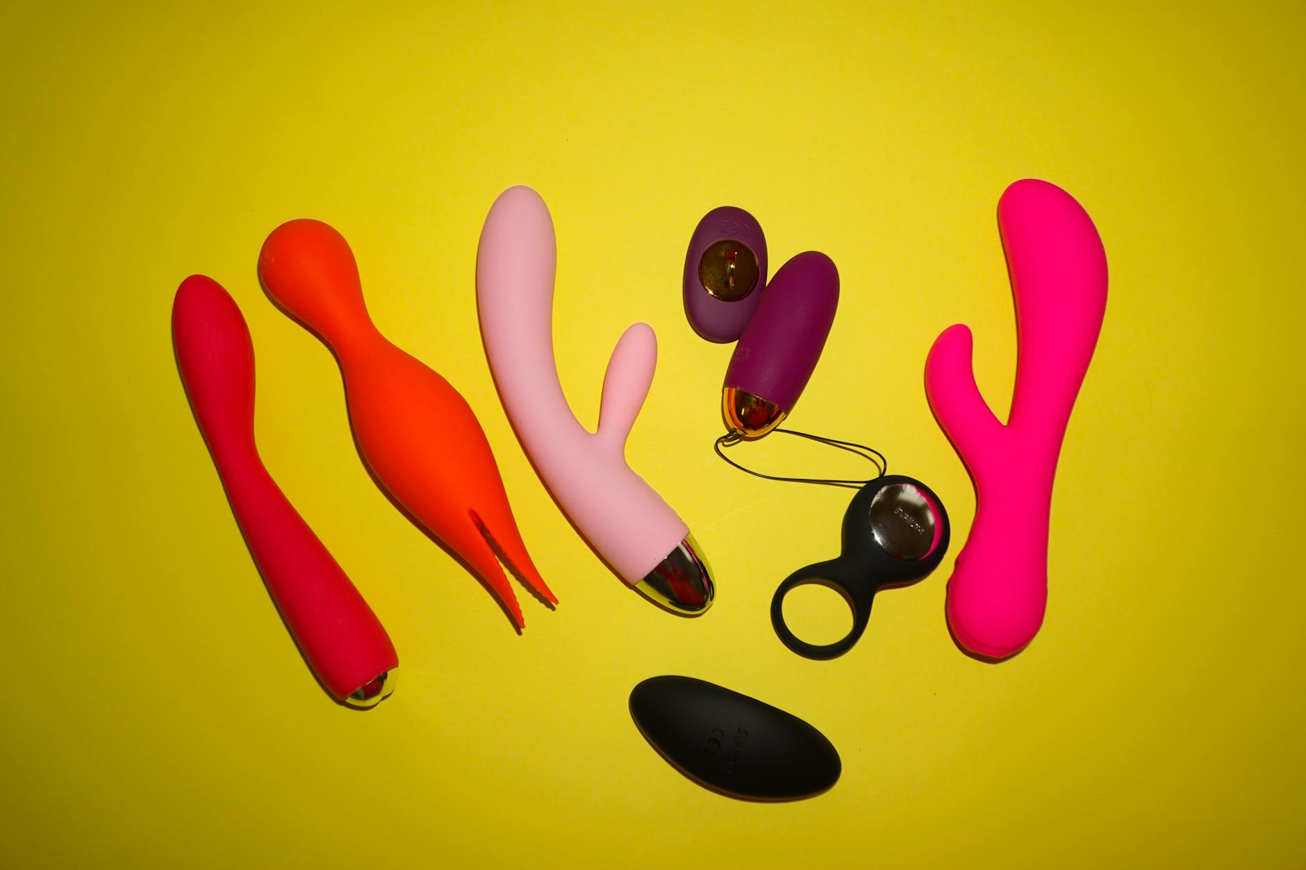 A yellow silicone vibrator surrounded by peeled bananas on a bright yellow background